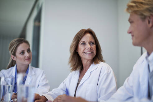 Female doctors smiling at male colleague in hospital - AJOF01330