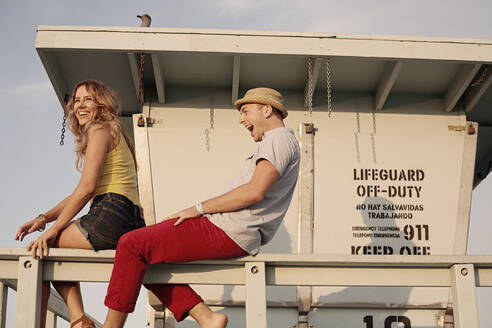 Beautiful woman sitting with boyfriend on railing at Santa Monica - AJOF01354