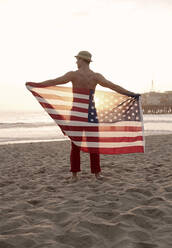 Junger Mann hält Flagge am Strand von Santa Monica - AJOF01356