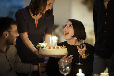 Überrascht Frau Blick auf weiblichen Freund hält Geburtstagskuchen zu Hause - MJRF00408