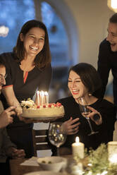 Männliche und weibliche Freunde lachen während einer Geburtstagsfeier zu Hause - MJRF00410