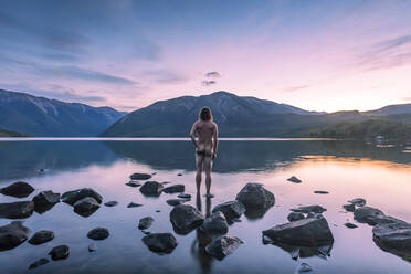 Neuseeland, Tasman, Rückansicht eines nackten Mannes mit Blick auf den Rototi-See bei Sonnenuntergang - WVF02022