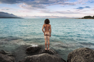 Neuseeland, Canterbury, Rückansicht eines nackten Mannes mit Blick auf den Lake Pukaki bei Sonnenuntergang - WVF02031