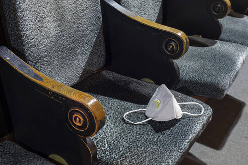 Protective face mask lying on seat in empty theater - VGF00379