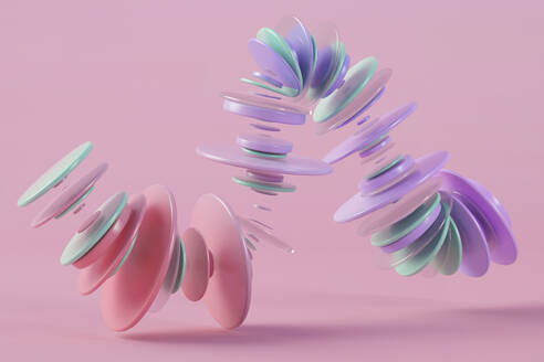 Three dimensional render of pastel colored rings floating against pink background - JPSF00222
