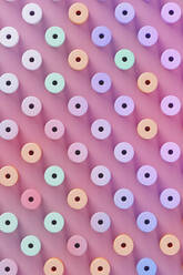 Three dimensional pattern of pastel colored cylinders standing against pink background - JPSF00227