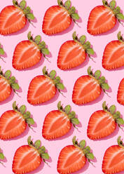 Muster von Reihen frischer halbierter Erdbeeren vor rosa Hintergrund - FLMF00420