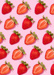 Muster von Reihen frischer halbierter Erdbeeren vor rosa Hintergrund - FLMF00423