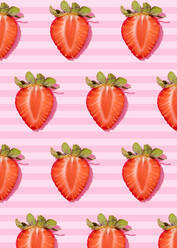 Muster von Reihen frischer halbierter Erdbeeren vor rosa gestreiftem Hintergrund - FLMF00427