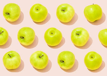 Pattern of green apples lying against light pink background - FLMF00438