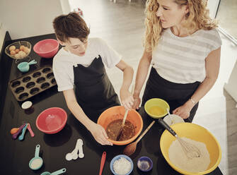 Junge lernt mit seiner Mutter in der Küche zu Hause die Zubereitung von Speisen - PWF00302