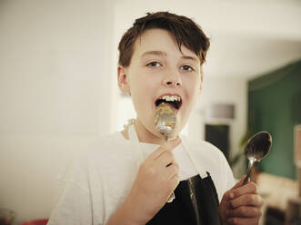 Boy licking muffin batter on spoon in kitchen - PWF00312