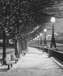 UK, England, London, Reihe von Straßenlaternen, die eine leere, schneebedeckte Promenade beleuchten - AHF00391