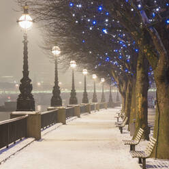 UK, England, London, Reihe von Straßenlaternen, die eine leere, schneebedeckte Promenade beleuchten - AHF00392
