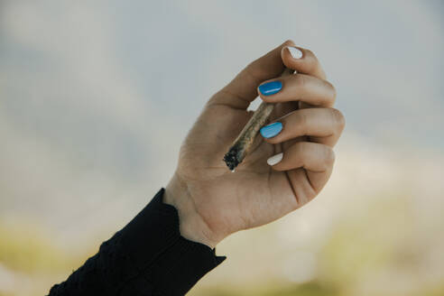 Junge Frau hält brennende Marihuana-Zigarette in der Hand - ACPF01232