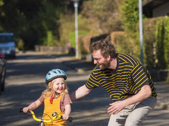 Glücklicher Vater bringt seiner Tochter im Freien das Radfahren bei - LAF02712