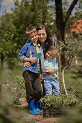 Lächelnde Mutter mit Sohn und Tochter im Hinterhof - ZEDF04218