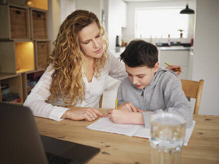 Mother teaching while son writing at home - PWF00342