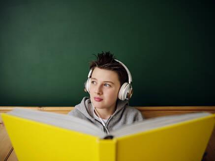 Cute boy wearing headphones looking away at home - PWF00349