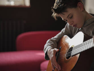 Boy learning guitar at home - PWF00365