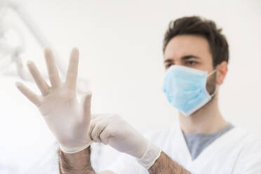 Male dentist wearing protective gloves at medical clinic - WPEF04480