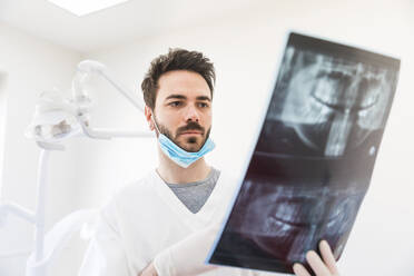 Männlicher Zahnarzt bei der Untersuchung von Röntgenbildern in einer medizinischen Klinik - WPEF04482