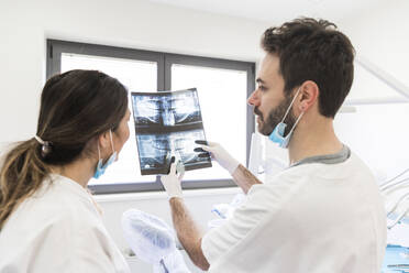 Männlicher Zahnarzt zeigt einer Assistentin in einer medizinischen Klinik ein Röntgenbild - WPEF04483