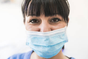 Female dentist wearing protective face mask during pandemic at clinic - WPEF04490