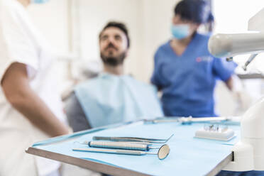 Dental equipments on tray with female dentists and male patient in background at medical clinic - WPEF04493