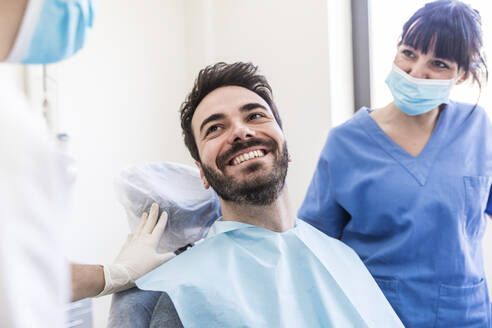 Lächelnder männlicher Patient mit weiblichen Zahnärzten in einer medizinischen Klinik - WPEF04494