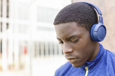 Young man listening music through wireless headphones - IFRF00627