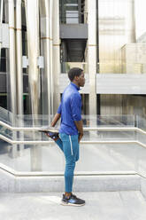 Young man stretching by railing on staircase - IFRF00632