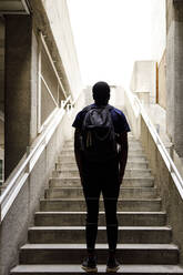 Junger Mann mit Rucksack vor einer Treppe stehend - IFRF00647