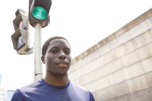 Afrikanischer Mann, der an einem sonnigen Tag vor einem Straßensignal steht - IFRF00655