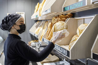 Bäckerin mit Maske bei der Arbeit in einer Bäckerei - IFRF00665