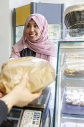 Lächelnde Kundin kauft Lebensmittel in einer Bäckerei - IFRF00668