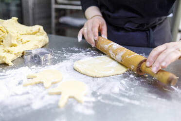 Bäckerin rollt Teig in einer Bäckerei - IFRF00700