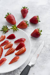 Küchenmesser und Teller mit frischen Erdbeeren auf weißem Marmor liegend - MAUF03756