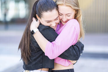 Happy female friends embracing in city - WPEF04502