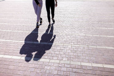 Schatten einer jungen Frau, die an einem sonnigen Tag auf einem Fußweg geht - WPEF04510