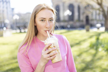 Schöne Frau trinkt Milchshake im öffentlichen Park - WPEF04515