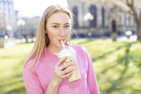 Schöne Frau trinkt Milchshake im öffentlichen Park - WPEF04515