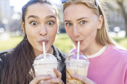 Überrumpelte Freundinnen trinken Milchshakes im Park - WPEF04518
