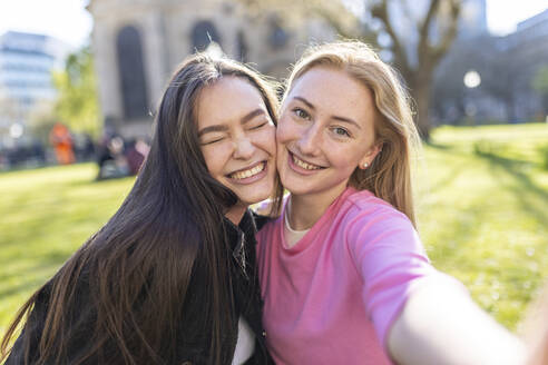 Glückliche Frauen mit Wange an Wange stehend im öffentlichen Park - WPEF04526