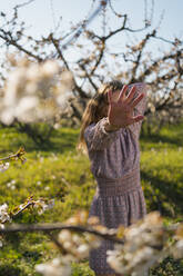 Woman showing stop gesture on cherry field - MAUF03776