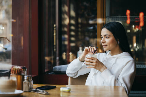 Frau schaut beim Kaffeetrinken im Café weg - OYF00360