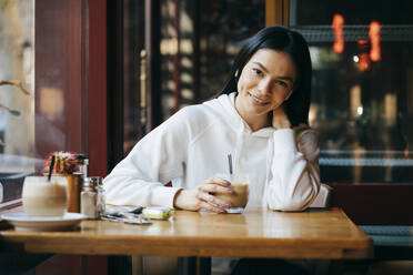 Lächelnde Frau mit Kaffee im Cafe sitzend - OYF00361