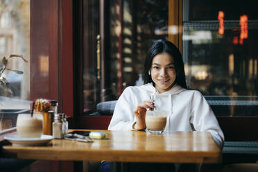 Happy woman having coffee at cafeteria - OYF00362