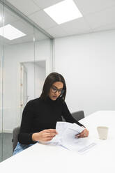 Weibliche Fachkraft geht Vereinbarungen durch, während sie im Sitzungssaal im Büro sitzt - JAQF00635