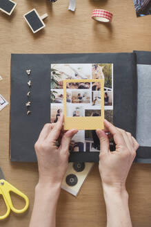 Woman holding frame over photo on scrapbook - SKCF00744